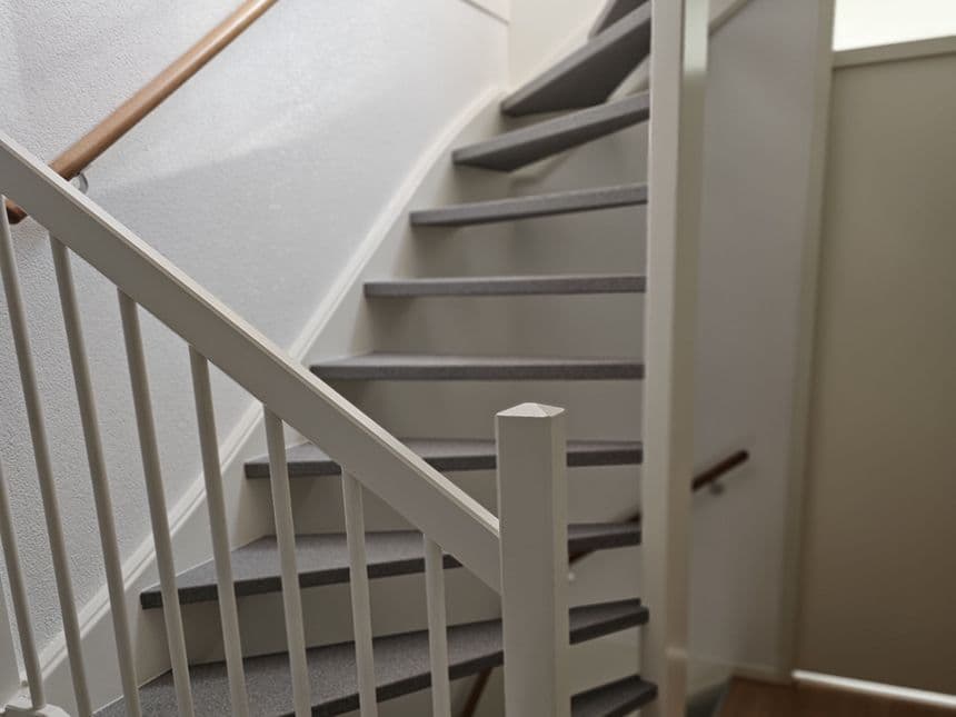 Starting situation of staircase before renovation — painted wooden staircase with grey treads and white spindles