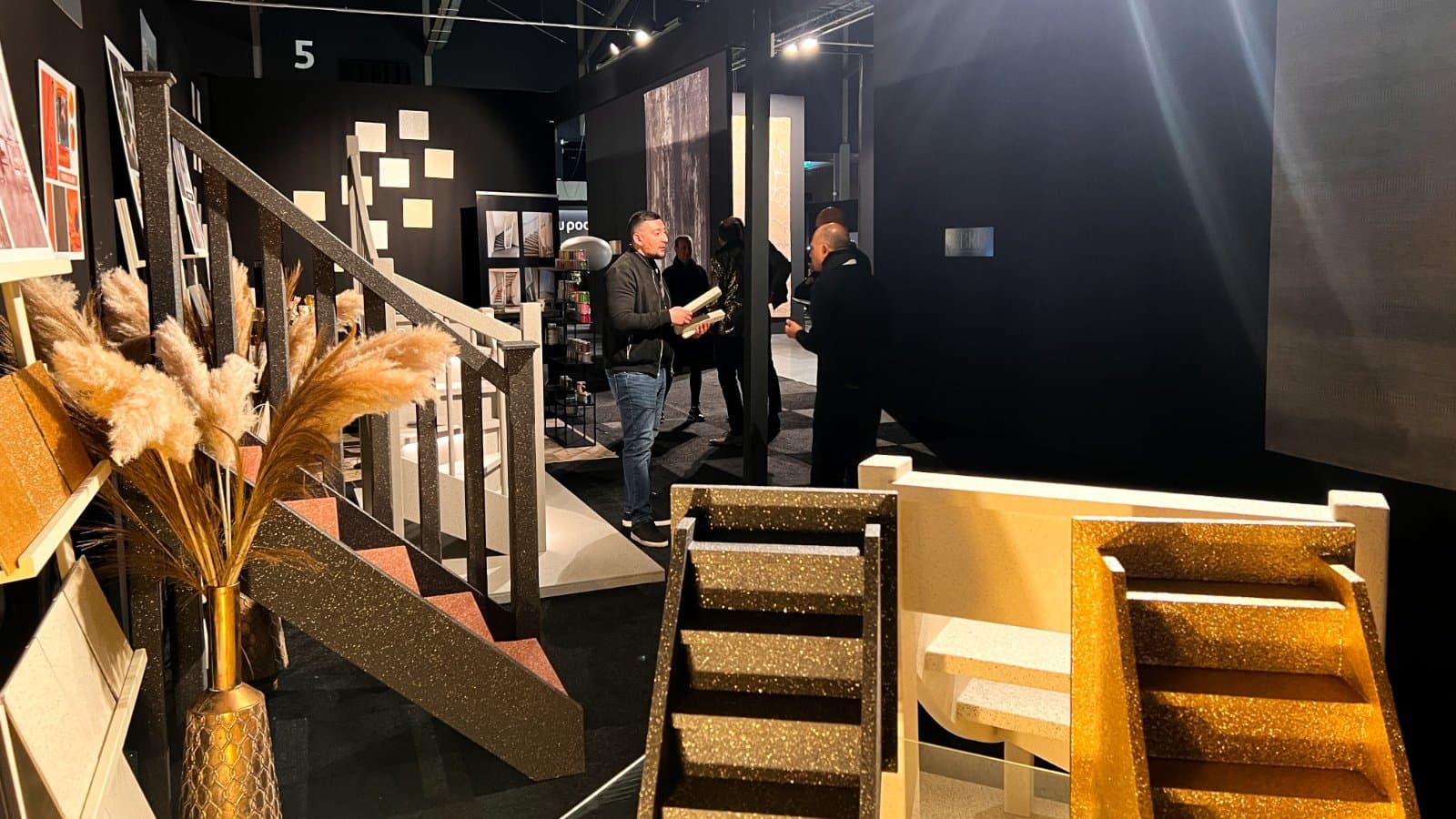 Trade fair stand with staircase models in recycled natural stone and visitors on the fair floor